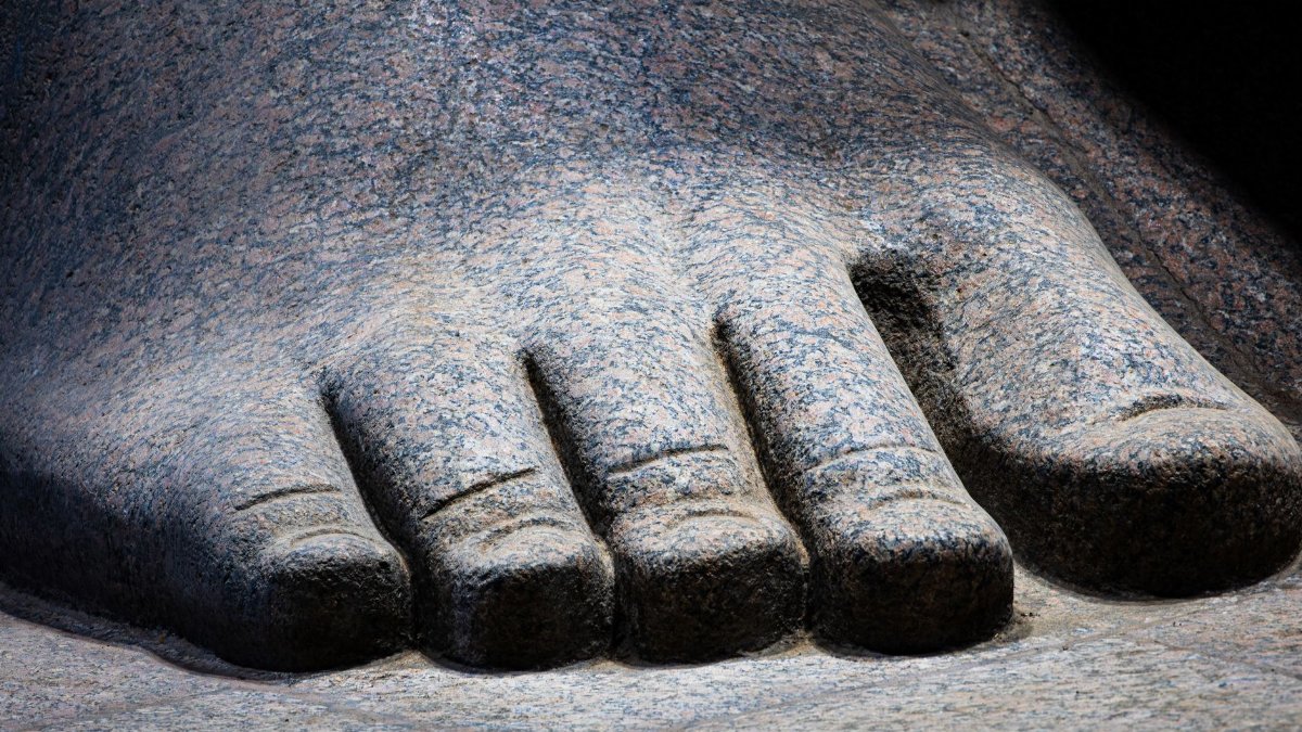 Detailed close-up of an ancient Egyptian statue's foot, highlighting its texture and craftsmanship.