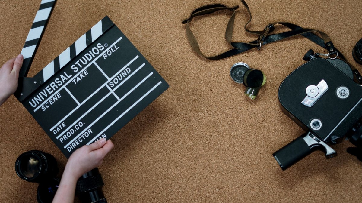 Top view of vintage film camera and clapperboard on cork background, evoking old cinema vibes.
