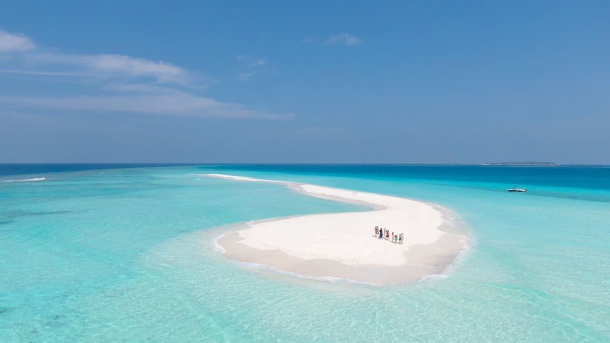 Aerial view of a sandbank in the Maldives with turquoise water and clear skies, ideal for vacation imagery.