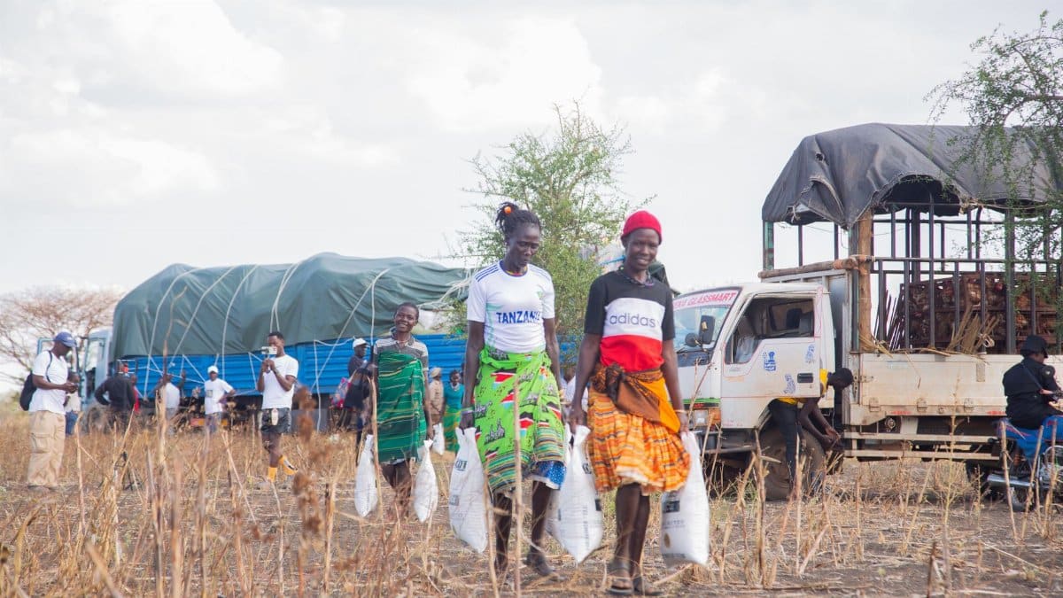Women participate in a community aid distribution event in a rural setting.