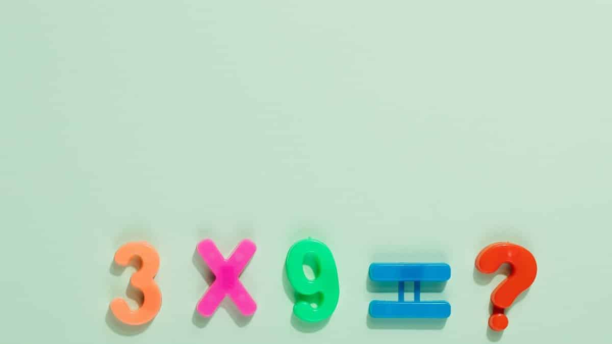 Colorful magnetic numbers and symbols on a pastel backdrop pose a math question.