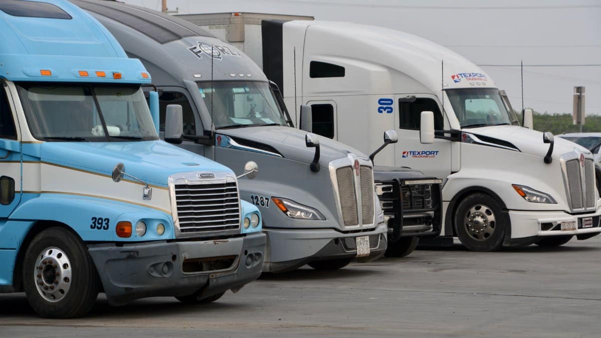 A row of parked semi trucks in Eagle Pass, Texas, showcasing various models and colors.