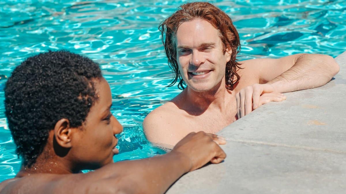 Two friends relaxing and chatting at a swimming pool during a sunny day. Enjoyment of vacation.