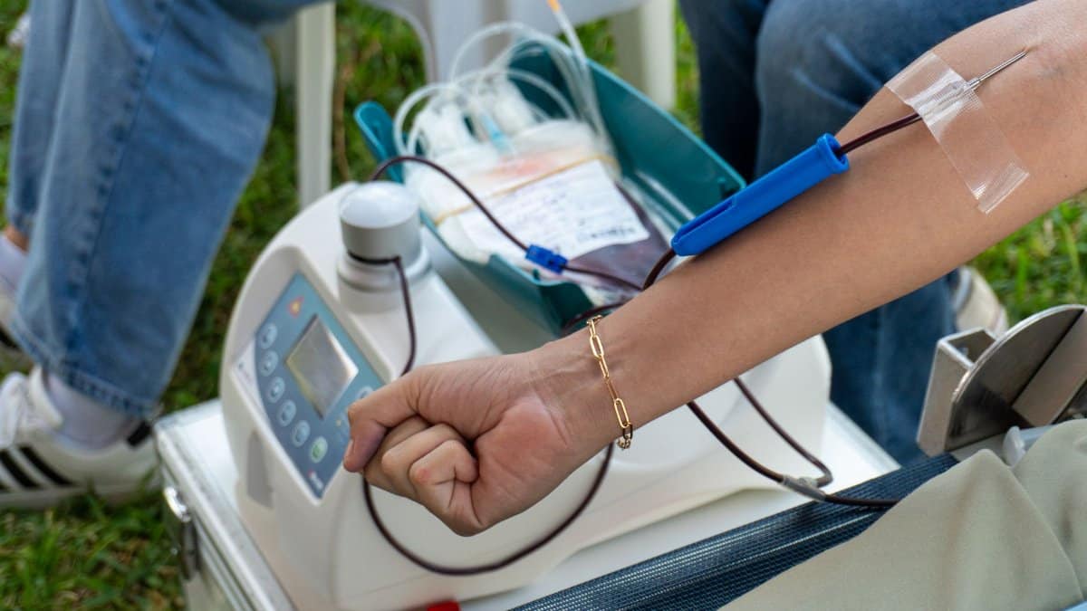 A close-up of the blood donation process outdoors in Piura, Peru, highlighting medical equipment and donor arm.