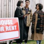 An interracial couple meets with a real estate agent to inquire about a house for rent.