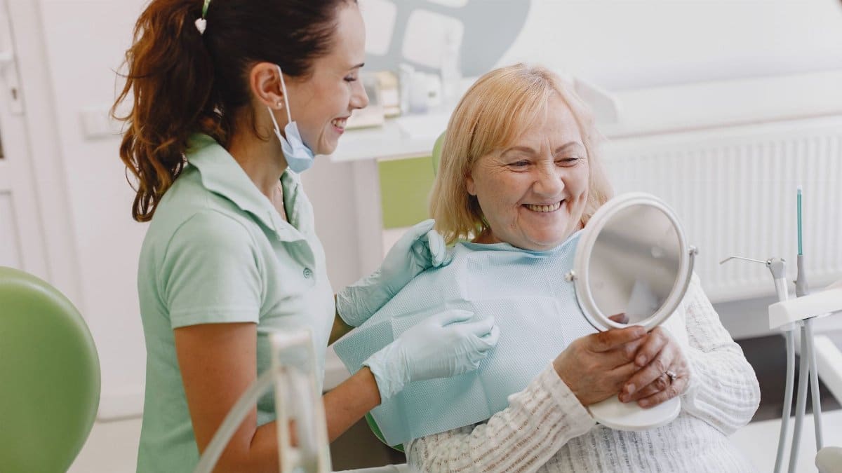 Senior patient at a dental check-up, smiling with the dentist in a modern clinic.
