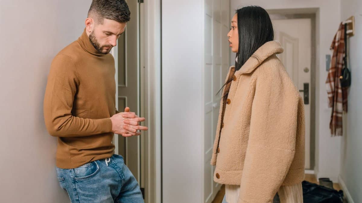 A man and woman having a serious discussion indoors, portraying relationship tension.