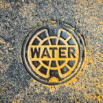 Colorful water utility cover on street pavement blends art with functionality.