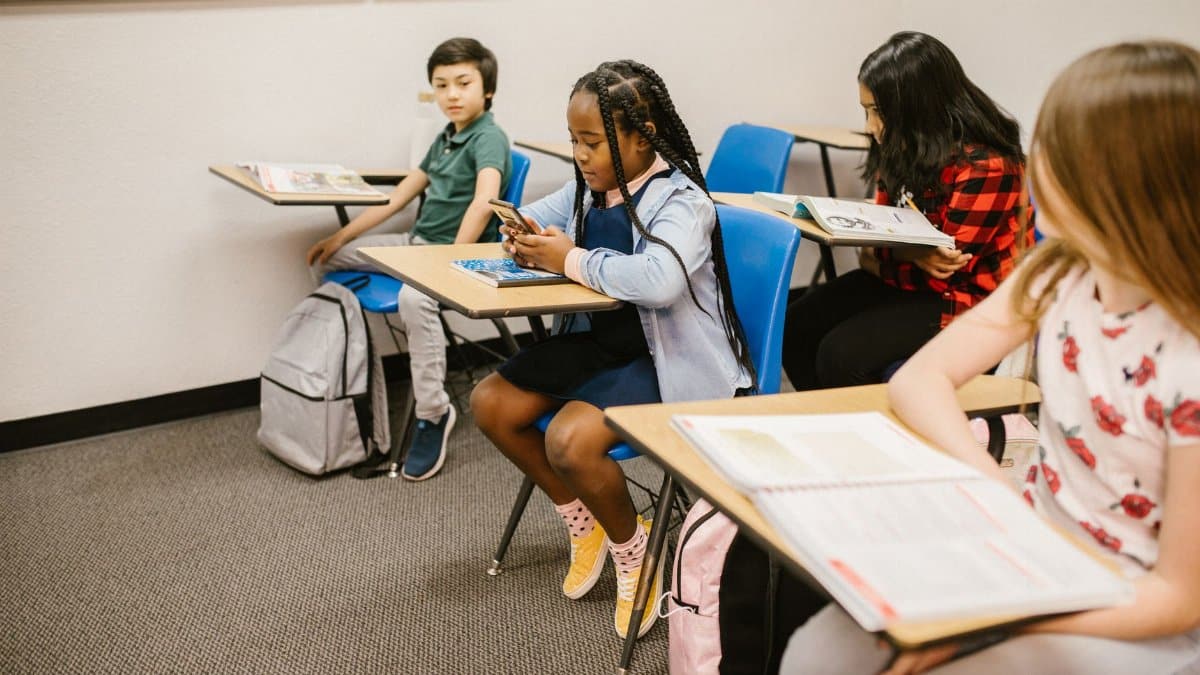 A diverse group of children in a classroom, focusing on social interactions and technology use.