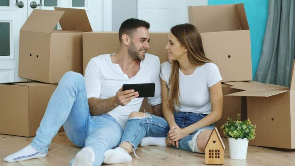 Happy couple relaxing with tablet among moving boxes in their new home.