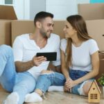 Happy couple relaxing with tablet among moving boxes in their new home.