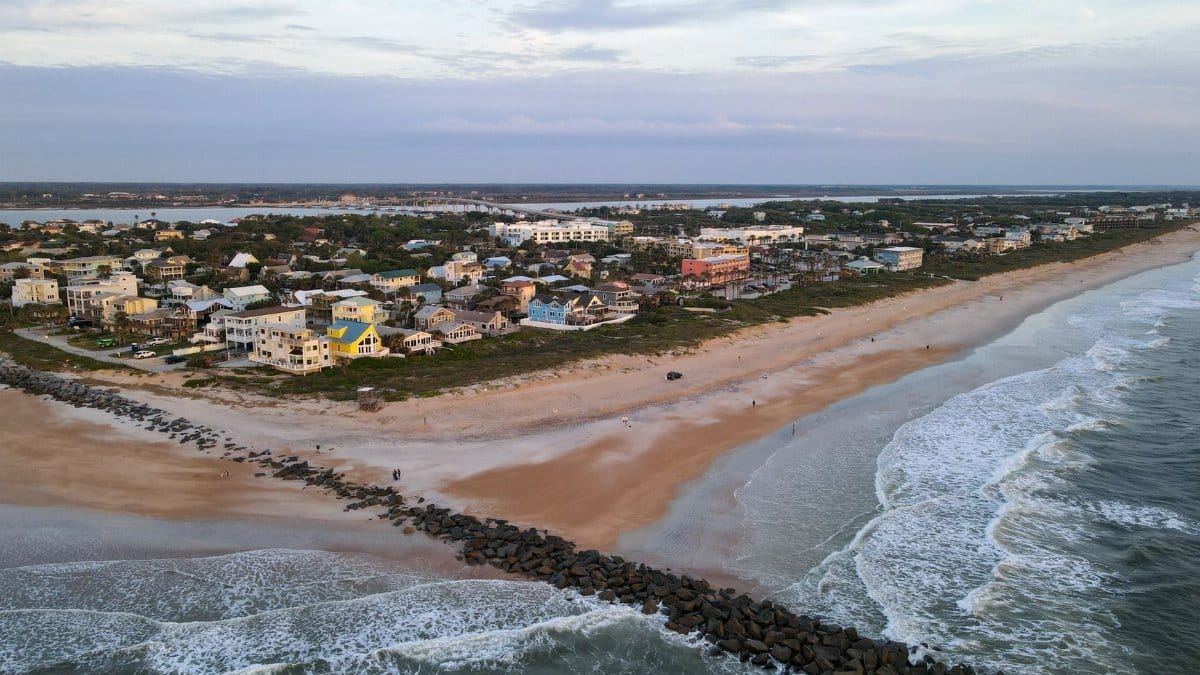 Scenic aerial photo of St. Augustine Beach, showcasing waves, sand, and coastal homes.