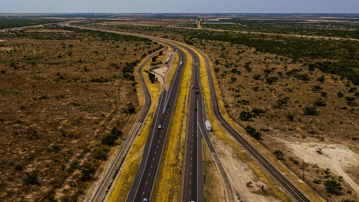 A scenic aerial shot of a highway cutting through the dry landscape of Midland, Texas.