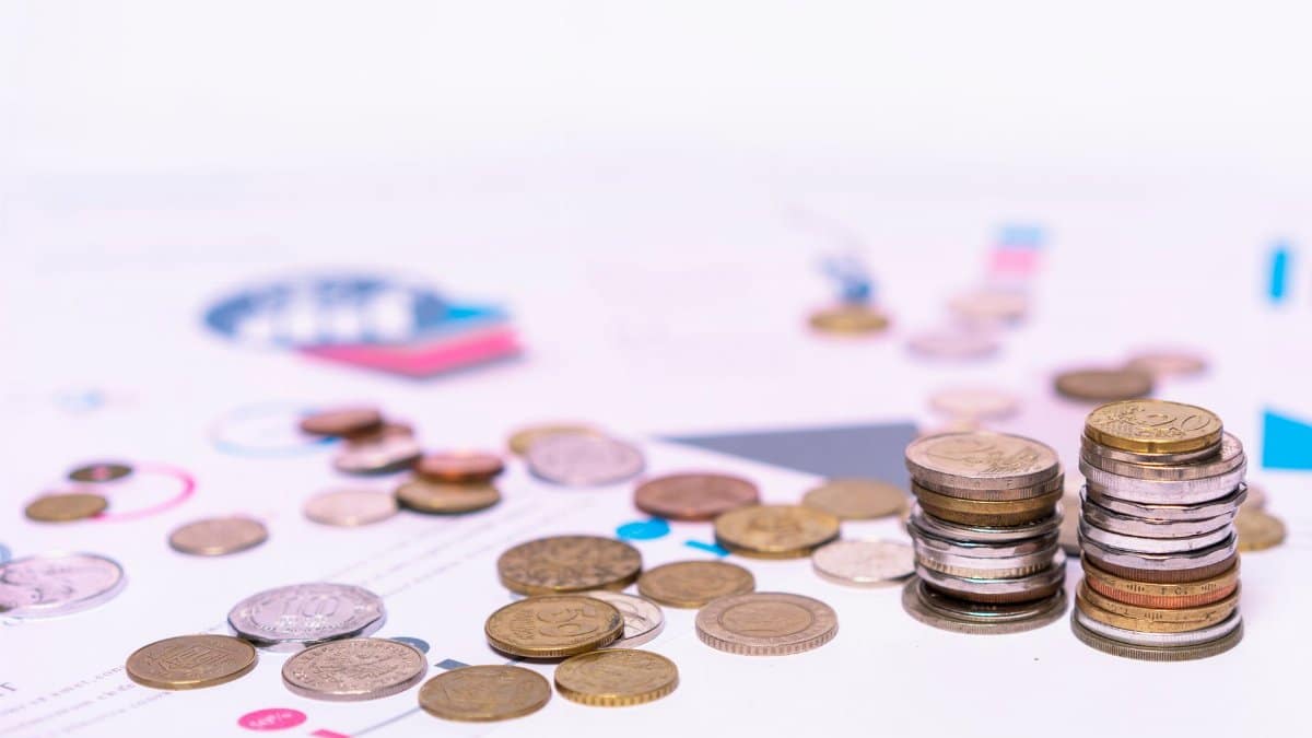 Stack of assorted coins with financial documents on a white background, highlighting the concept of savings.