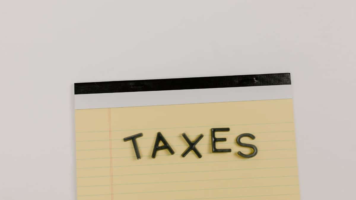 A flat lay of the word 'TAXES' on a yellow notepad, ideal for financial content.