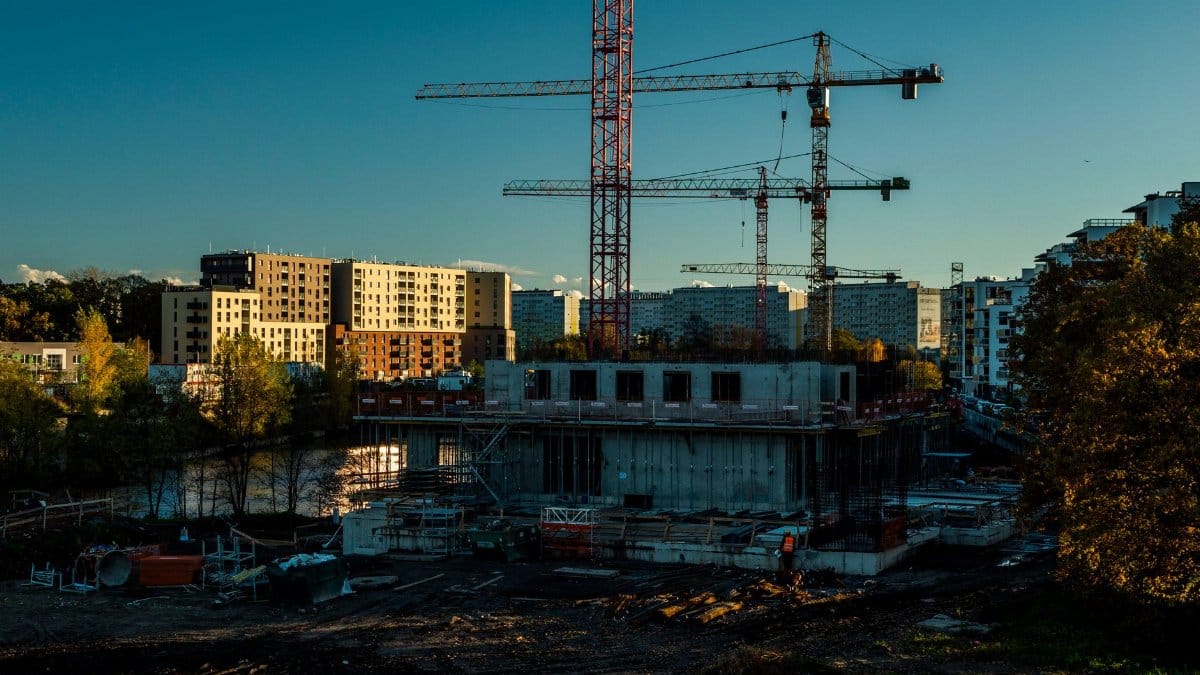 A vibrant urban construction scene with cranes and buildings under a twilight sky.