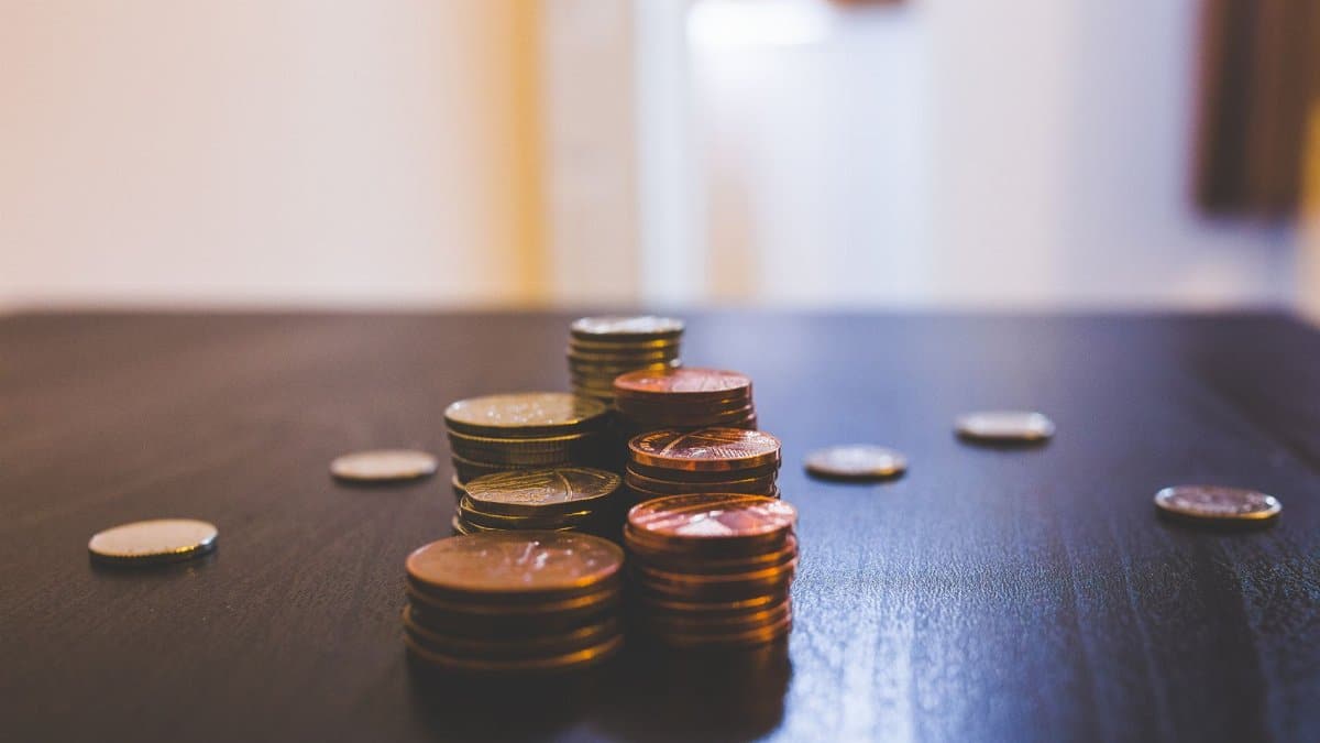 Close-up of various coins stacked on a dark table indoors.