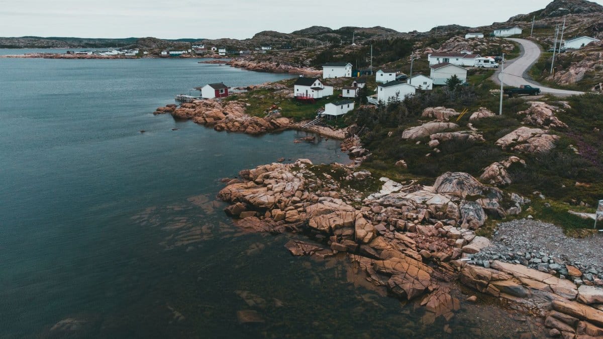 Scenic aerial view of a coastal village with rocky shoreline and serene ocean.