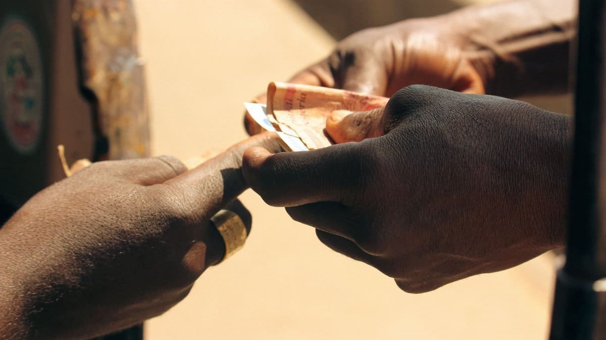 A detailed close-up of two hands exchanging paper currency outdoors, highlighting personal finance.