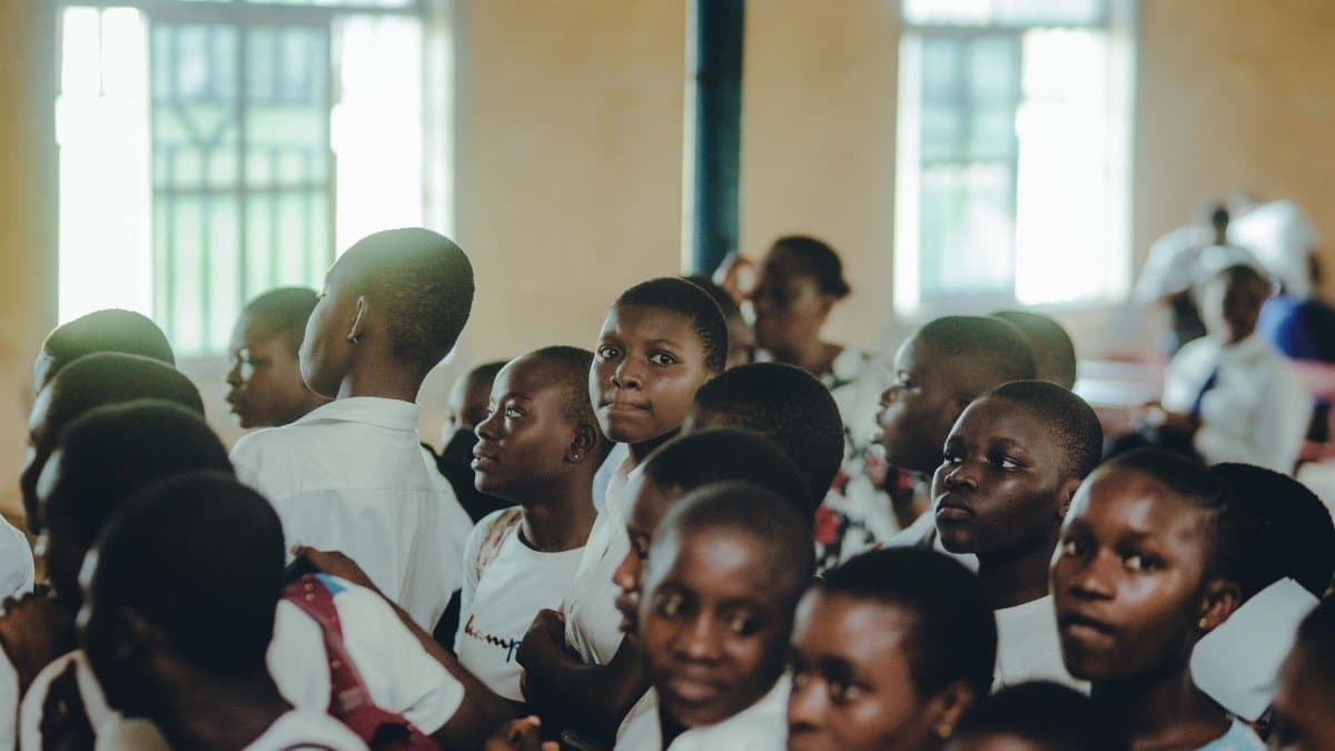A diverse group of students attentively participating in an indoor school assembly.