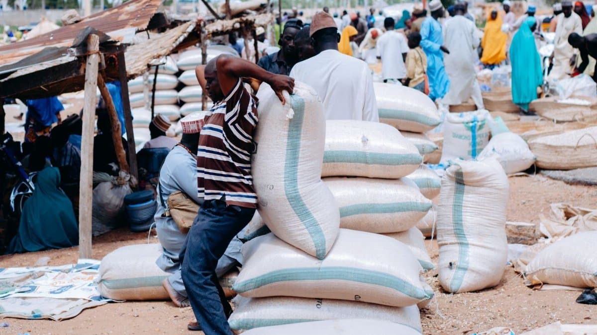 Bustling African market scene with people and large bags of grain, showcasing daily life.