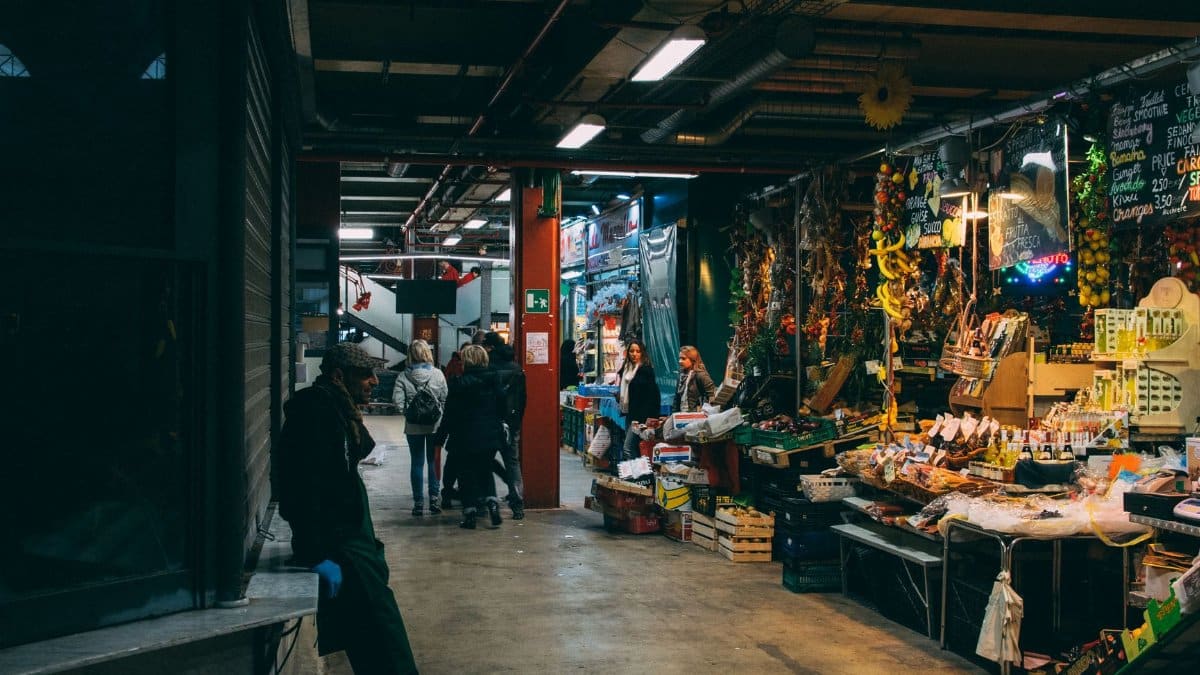 Bustling indoor market scene in Florence, Italy, showcasing local goods and people shopping.