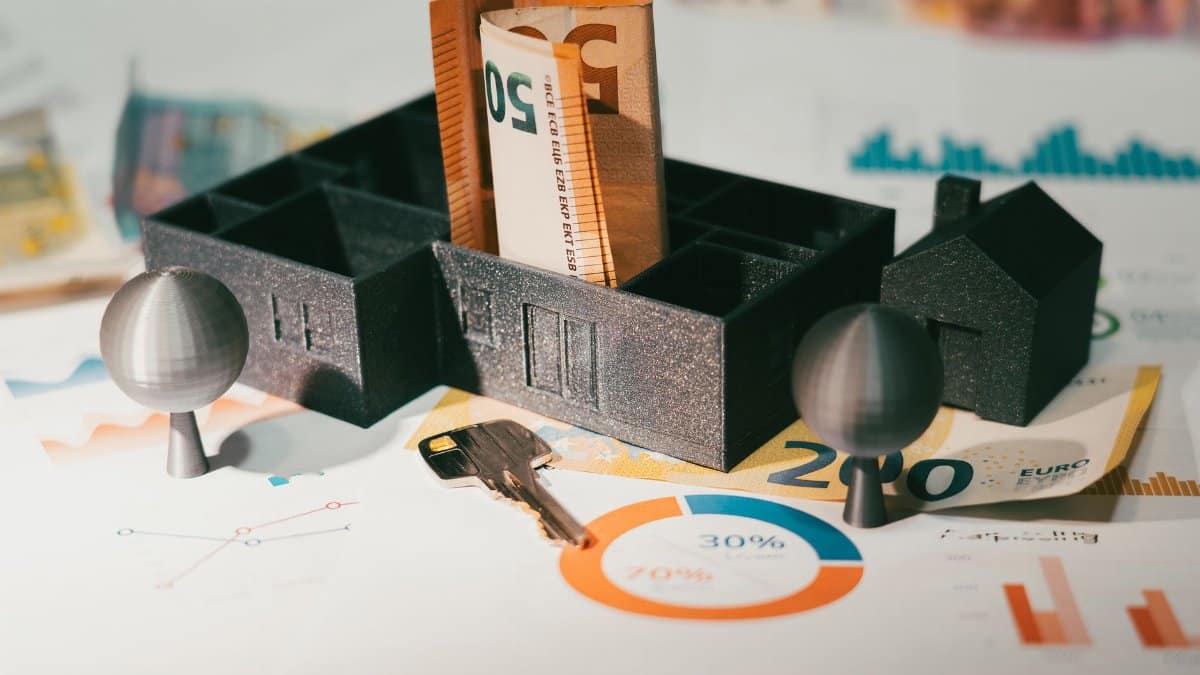 Euro notes with house model and financial charts symbolize real estate investment and economic growth.