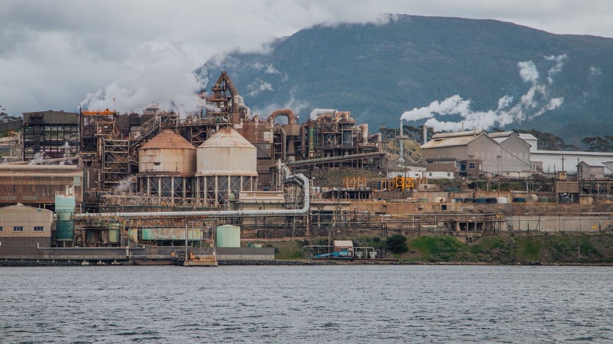 View of an industrial refinery against Mount Wellington in Hobart, Australia, by a river.