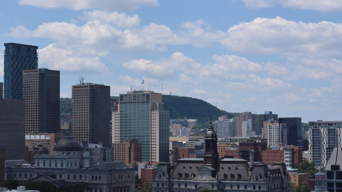 Scenic view of Montreal's skyline with Mount Royal in the background under a blue sky.