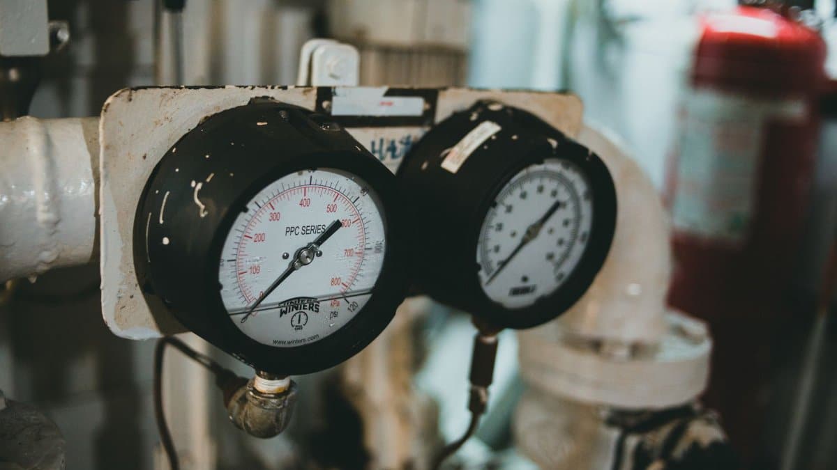 Detailed close-up of industrial pressure gauges set against a blurred machine background.