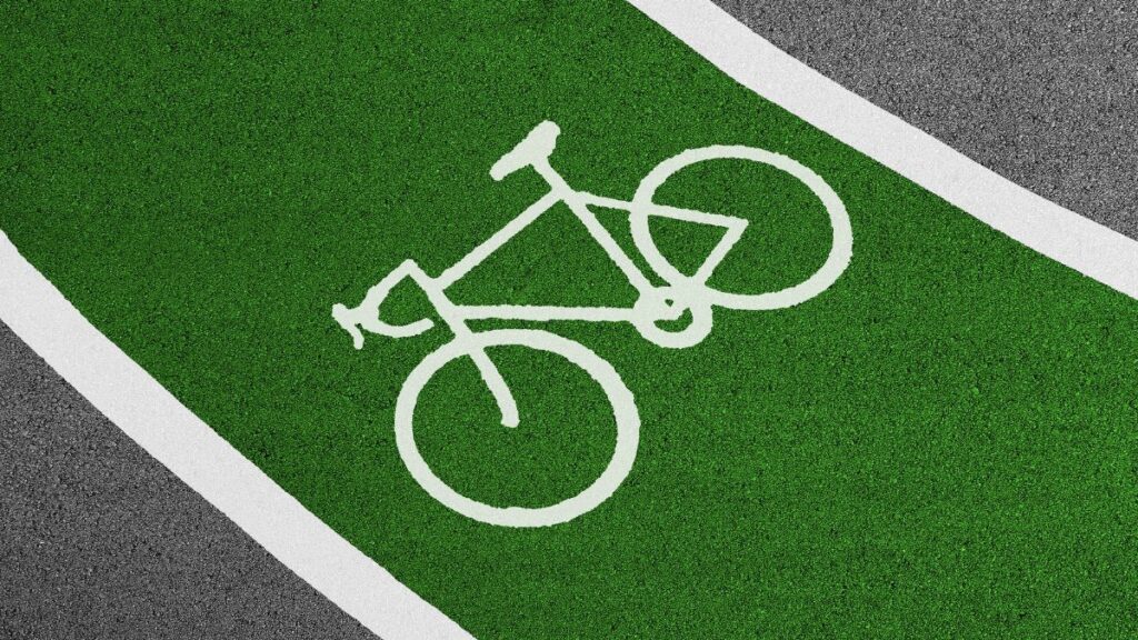 Bright green bicycle lane with white bike symbol and clear road texture.