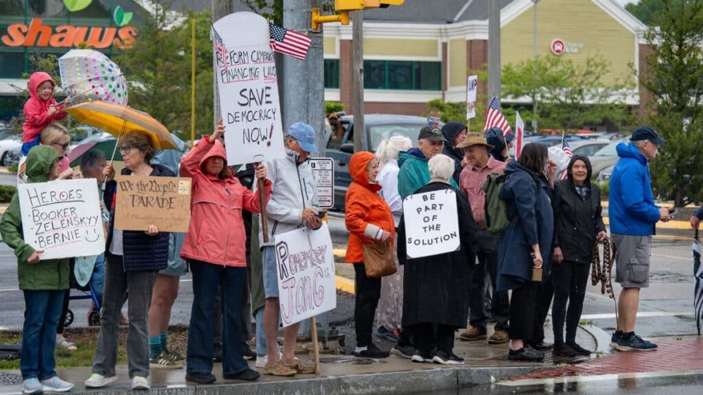 A group of people gathered in South Kingstown holding signs for democracy and political change.
