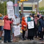 A group of people gathered in South Kingstown holding signs for democracy and political change.