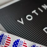 I Voted stickers with an American flag design and Voting Day sign symbolize U.S. electoral participation.