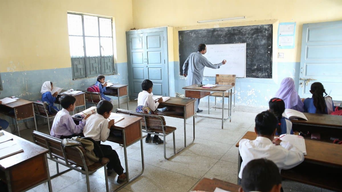 Elementary classroom with attentive students and teacher at blackboard, promoting education.