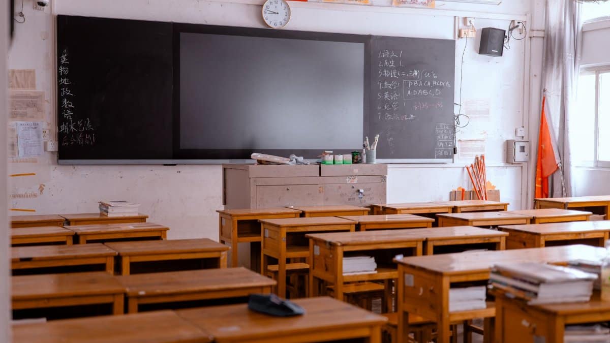 An empty classroom with wooden desks and a blackboard, featuring educational materials.