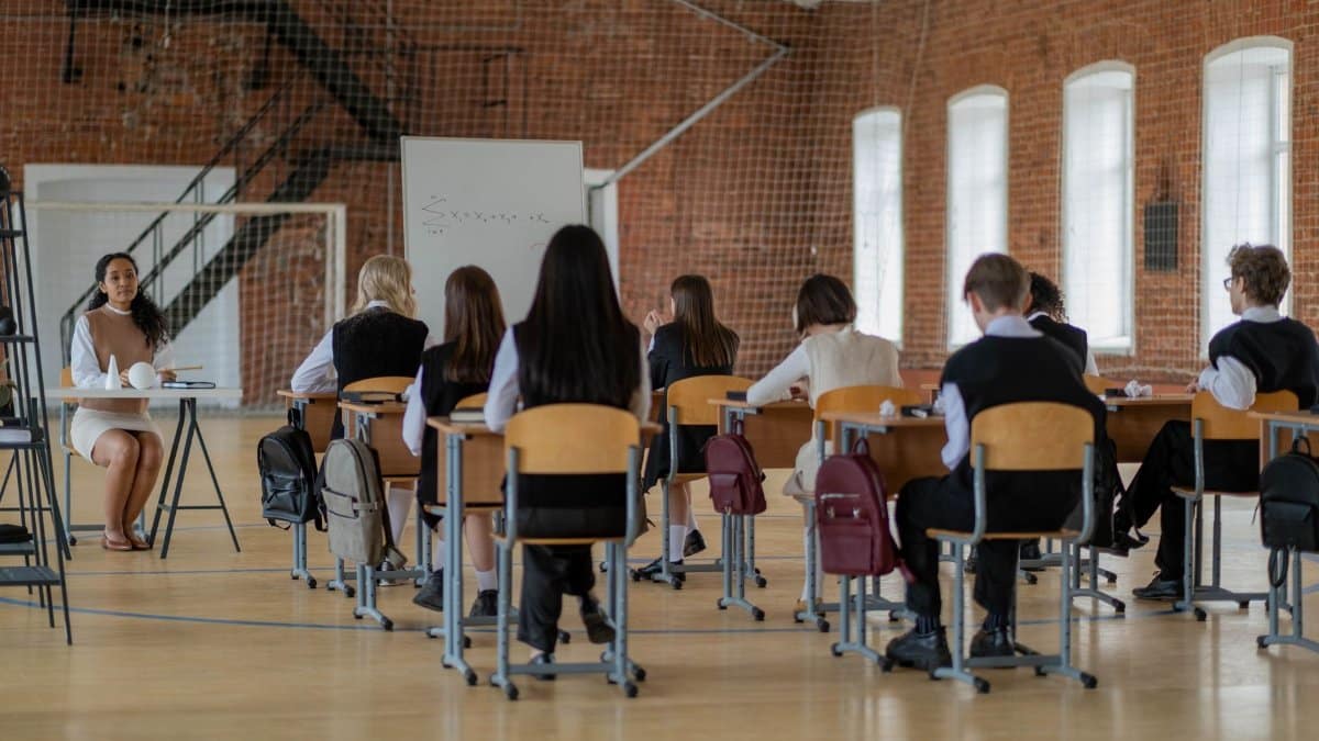 Students in a classroom setting facing a teacher, engaged in education.