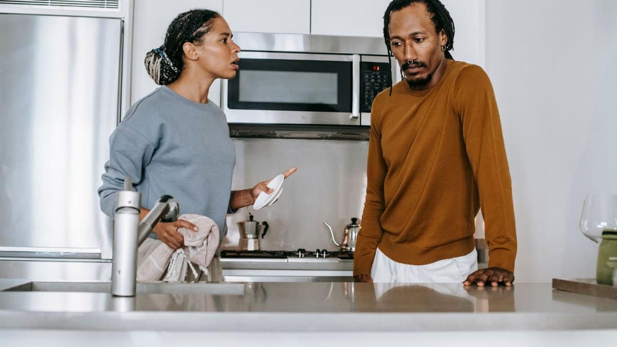 African American guy and lady in casual clothes standing and arguing in kitchen in daytime