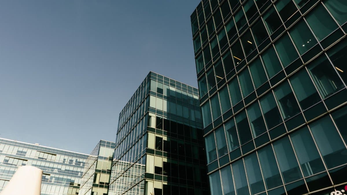 Elegant modern glass office buildings with reflective windows under a clear blue sky, showcasing urban architecture.