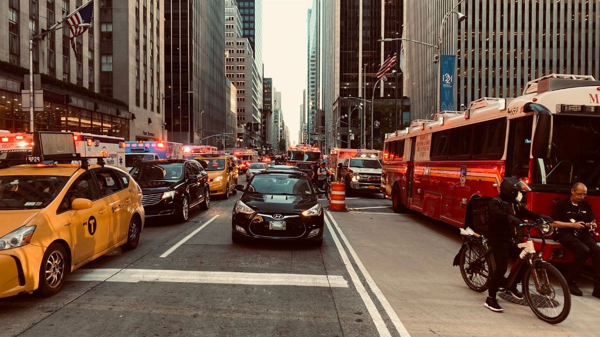 Dynamic scene of New York City traffic amid towering skyscrapers, vibrant urban life.
