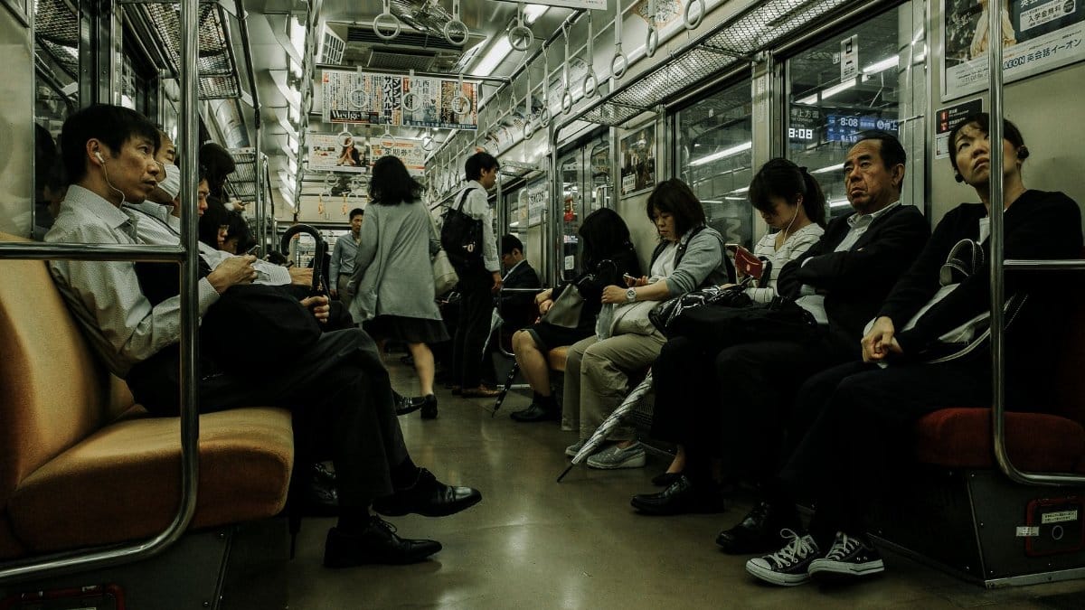 Passengers seated and standing in a busy subway train, showcasing daily public transportation.