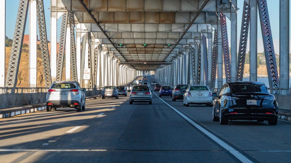 Traffic flows on a steel bridge under the blue sky, depicting daily commute and transportation.