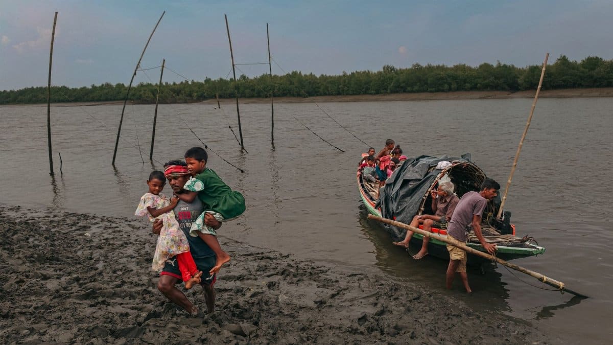 Family with children navigating muddy riverbank after boat ride, depicting rural life.