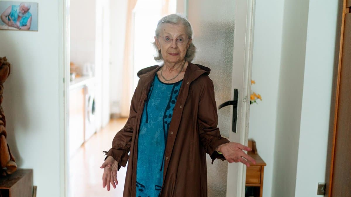 Elderly woman standing in a doorway, inside a home in Prague, showcasing daily life.