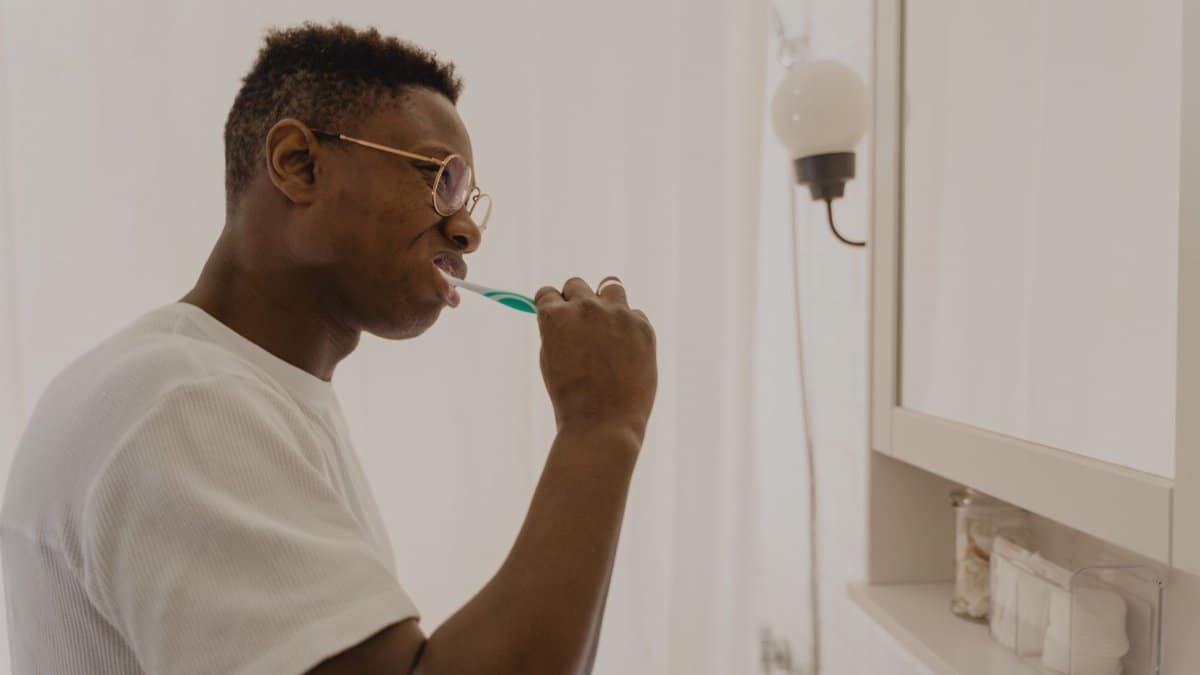 Man brushing his teeth in a bathroom, focusing on daily oral care and hygiene.