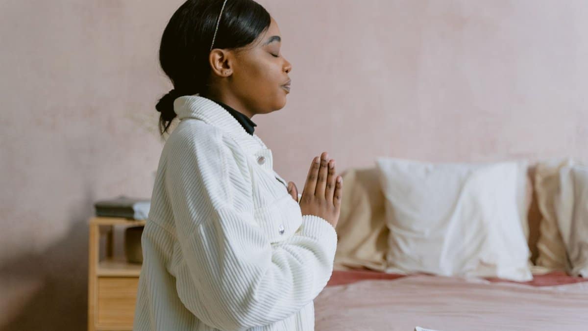 A serene image of a woman with closed eyes in prayer, capturing a moment of spiritual reflection indoors.