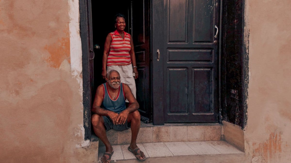 Senior couple relaxing at their doorway on a warm day, showcasing a moment of everyday life.