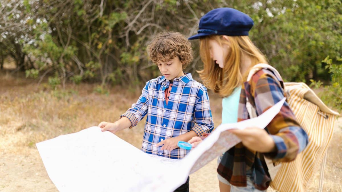 Two children exploring outdoors with a map, showcasing adventure and exploration.