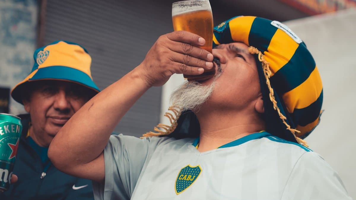Soccer fan enjoying a beer in vibrant team colors, showing spirited support.