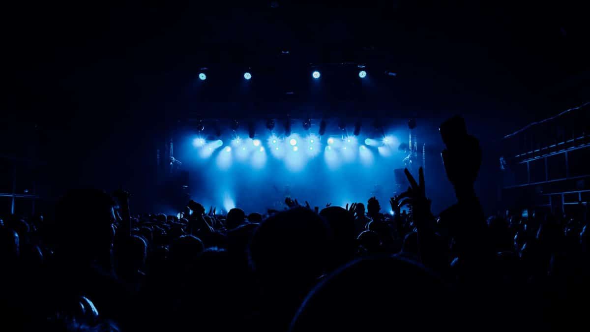 A vibrant concert scene with a lively crowd and dramatic blue stage lighting.